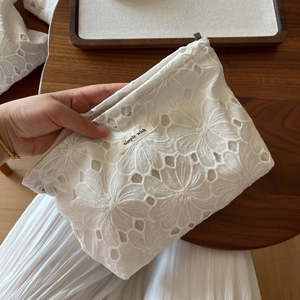 Detail of white cotton lace embroidery tote bag with floral patterns and a metal zipper