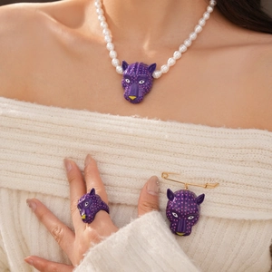 Détail macro d'une parure bijoux tête de léopard violette avec collier, bague et broche.