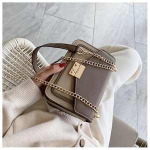 Detail view of khaki and brown crossbody bag with gold chain strap and metal clasp