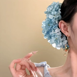 Detail of light blue fabric flower hair pin with colorful beaded tassels on model