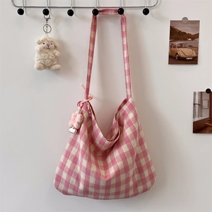 Detailed view of pink plaid canvas hobo bag with flower charm and plush sheep decoration