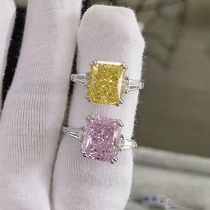 Detailed view of yellow and pink radiant cut gemstone rings on white gloved hands
