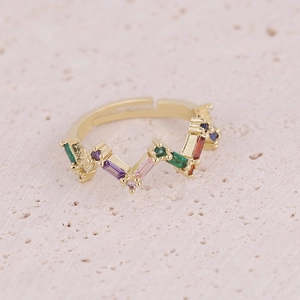 Gold open ring with colorful rectangular zircon stones on pink stone background