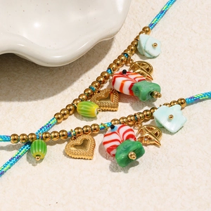 Vue macro des pendentifs cœur et étoile dorés 18K sur un collier de perles colorées