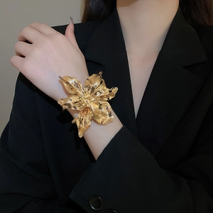 Close-up of golden oversized floral cuff bracelet with artistic metallic petal textures