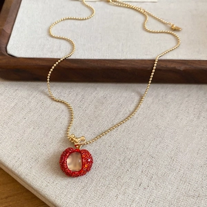 Close-up of sweet apple pendant necklace with red crystals and gold bead chain