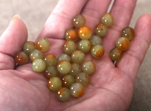 Close-up of olive green natural stone round beads for DIY jewelry making held in hand