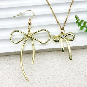 Golden bow jewelry set featuring a tassel earring and rhinestone pendant necklace