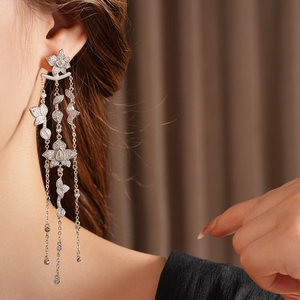 Detail of silver tassel earrings with zircon flower and leaf charms worn by a model