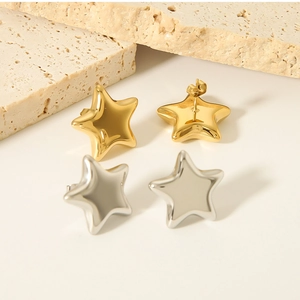 Detail of gold and silver star earrings on a textured stone surface, minimalist design