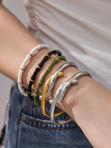 Dettaglio di cinque bracciali con motivi in smalto bambù e design in metallo intrecciato
