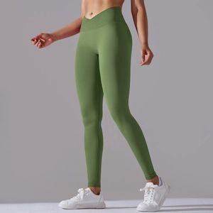 Detail of high-waist yoga leggings with crossover waistband in seamless green fabric