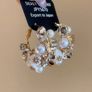 Detail of vintage flower pearl hoop earrings with crystal inlay on a card