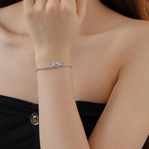 Close-up of a silver knot heart bracelet with pave-set zircons on a model's wrist
