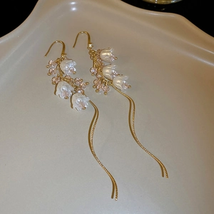 Détail de boucles d'oreilles muguet avec perles fleurs blanches et pompons en cristal