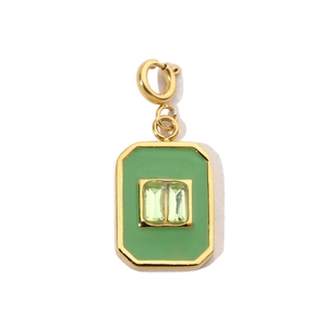 Macro shot of rectangular gold charm with green enamel and emerald-cut gemstones