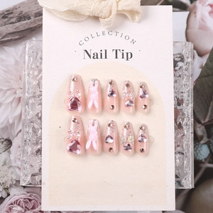 Detail of pink press-on nails featuring 3D rabbit, heart gems, and glitter gradient finish