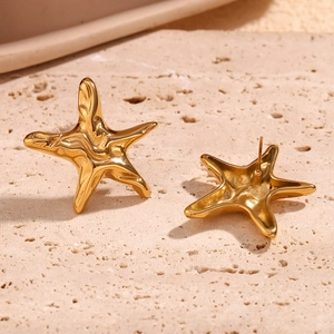 Golden starfish stud earrings with irregular texture on a natural stone base