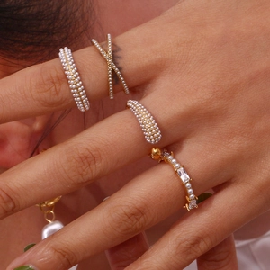Detail of elegant gold-plated rings with white pearls and zircons worn on hand