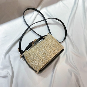 Detailed view of woven straw crossbody bag with black leather trim and metal clasp