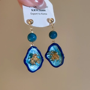 Détail macro de boucles d'oreilles vintage avec breloques en émail bleu et accents dorés