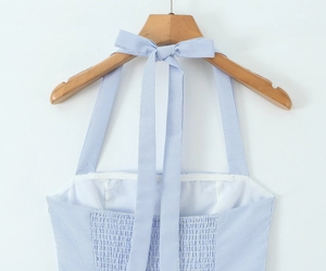 Detail of blue and white striped dress featuring bow tie straps and elastic smocked back