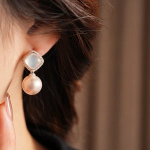 Close-up of pearl earrings with square zircon and lavender pearls on a model ear