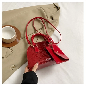 Detail of red crocodile textured handbag with detachable mini pouch and gold hardware