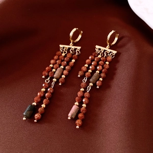 Détail de boucles d'oreilles vintage en or avec perles dépolies sur fond de soie