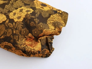 Detail van goud en donkerbruine bloemen jacquard stof voor elegante V-hals jurk
