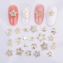 Detailed view of hollow and rhinestone-encrusted gold star nail art charms on nails