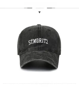 Detail view of white ST.MORITZ embroidery on washed black cotton baseball cap fabric