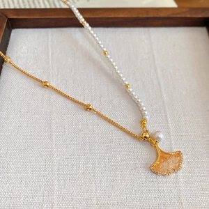 Close-up of asymmetric ginkgo leaf necklace with pearls and fine gold plating
