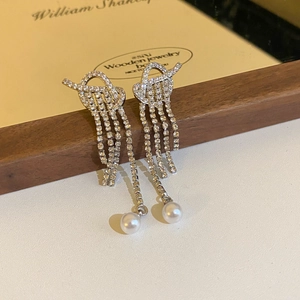 Close-up of knot tassel earrings with sparkling rhinestones and a hanging faux pearl
