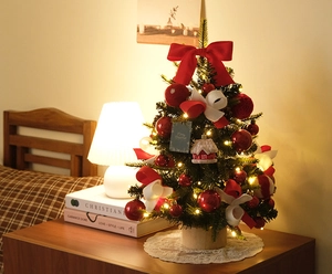Detail of a mini DIY Christmas tree with red bows and warm LED lights on a wooden base