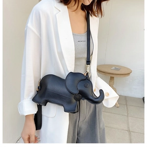 Detail showing a black elephant shaped crossbody bag with gold hardware on a model