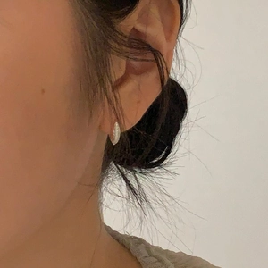 Close-up of minimalist 925 silver hoop earrings with zircon stones worn by a model