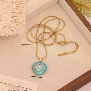 Detailed macro view of heart turquoise pendant with evil eye on a gold snake chain necklace