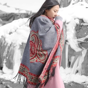 Ethnic cashmere shawl with red paisley pattern and black tassels in a winter snowy scene