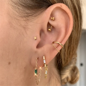 Detail of gold ear cuff and earring set with emerald-cut green gems and tassels