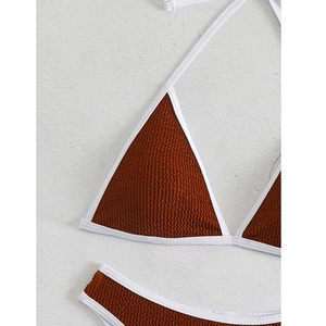 Detailaufnahme des braunen Seersucker-Bikinis mit weißer Paspelierung und Bindebändern