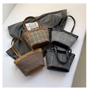 Detail of wool plaid bucket bags in brown black and grey with PU leather patchwork