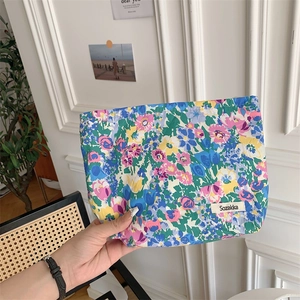 Close-up of small floral cotton makeup bag with Sozakka brand label held in hand