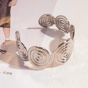 Detailed view of silver spiral geometric metal bracelet with textured swirl pattern