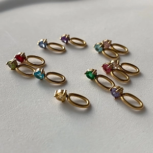 Makroaufnahme bunter Geburtsstein-Anhänger mit polierten goldenen Metallringen