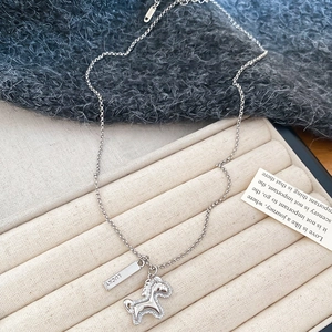 Detailed close-up of lucky letter plate and zircon-studded horse pendant on silver necklace