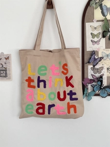 Detail of colorful towel embroidery and magnetic buckle on beige canvas tote bag