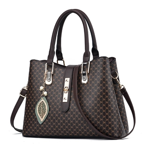 Elegant women's brown monogram tote bag with double handles and metal leaf pendant