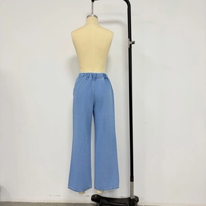 Dettaglio dei pantaloni in denim azzurro a gamba larga con vita alta elasticizzata
