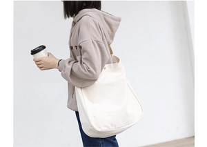 Side view of white canvas tote bag worn by model for daily commute and casual style